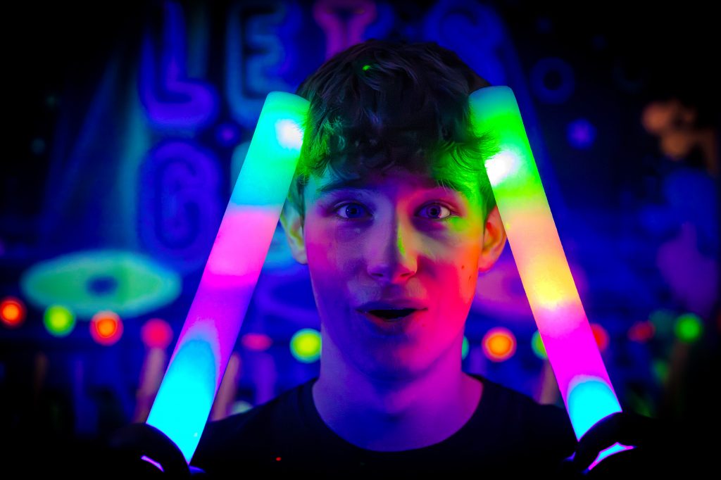 Entertainer Blair from Treasure Box Parties holding LED batons at Darcie’s Glow Disco birthday party in Bagshot. Creating a colourful and dynamic UV party experience for children in Bagshot and surrounding areas.