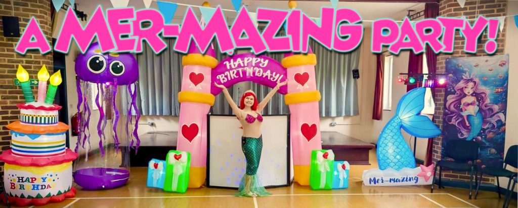 Mermaid party entertainer standing under inflatable pink princess castle arch, with LED jellyfish, mermaid tail and birthday decorations at Mayford Village Hall near Woking