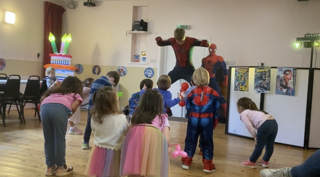 Children taking part in organised games at a Spiderman themed birthday party in Surrey