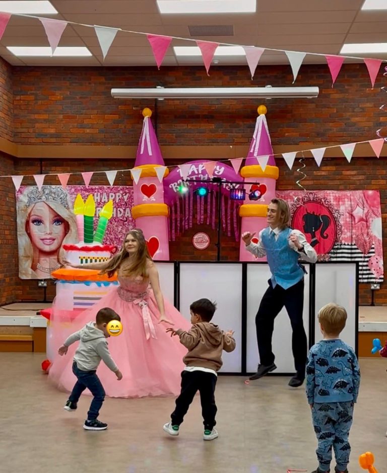 Barbie and Ken entertainers dancing with children in front of a Barbie themed castle