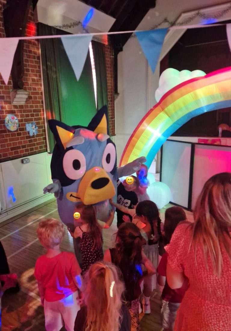Bluey mascot dancing with children beside a rainbow inflatable