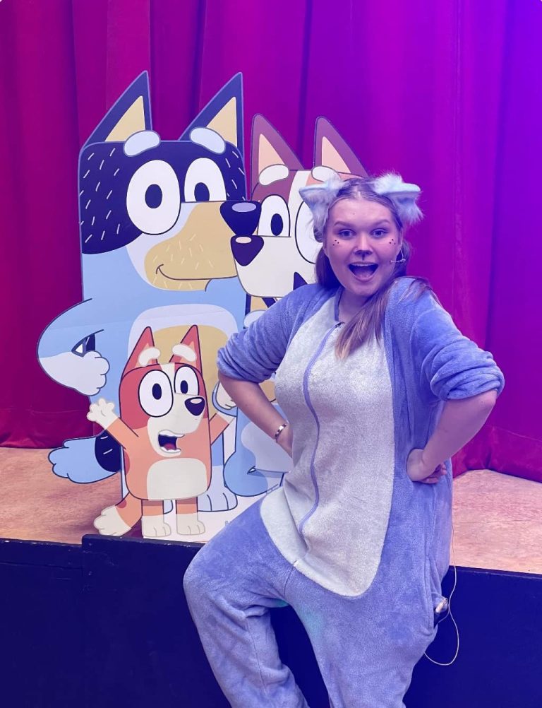 Entertainer in a Bluey costume posing in front of a Bluey cut-out