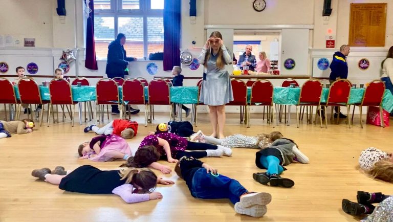 Children lying still on the floor during a game of sleeping lions