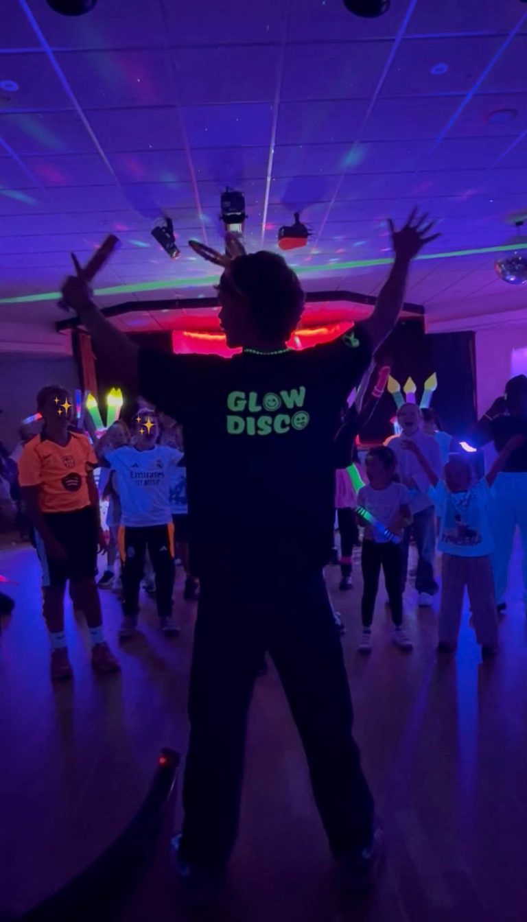 Glow disco entertainer dancing with children under UV lights