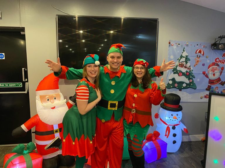 Three elf entertainers with Santa and snowman inflatables