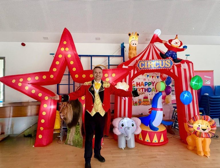 Ringmaster entertainer in front of a circus tent setup with animal inflatables