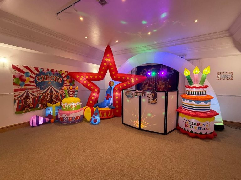 Circus backdrop, light-up star and cake inflatables around the DJ booth