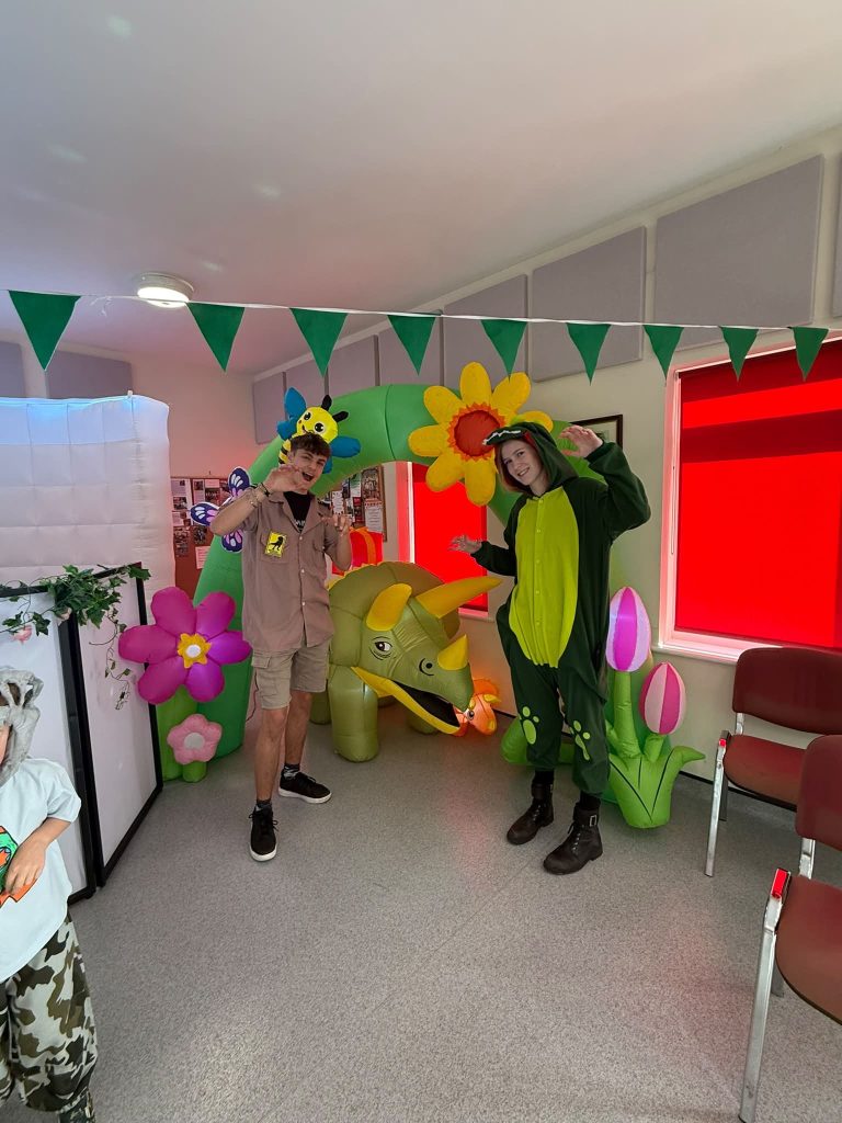 Explorer entertainer and a dinosaur costume character in a jungle setup