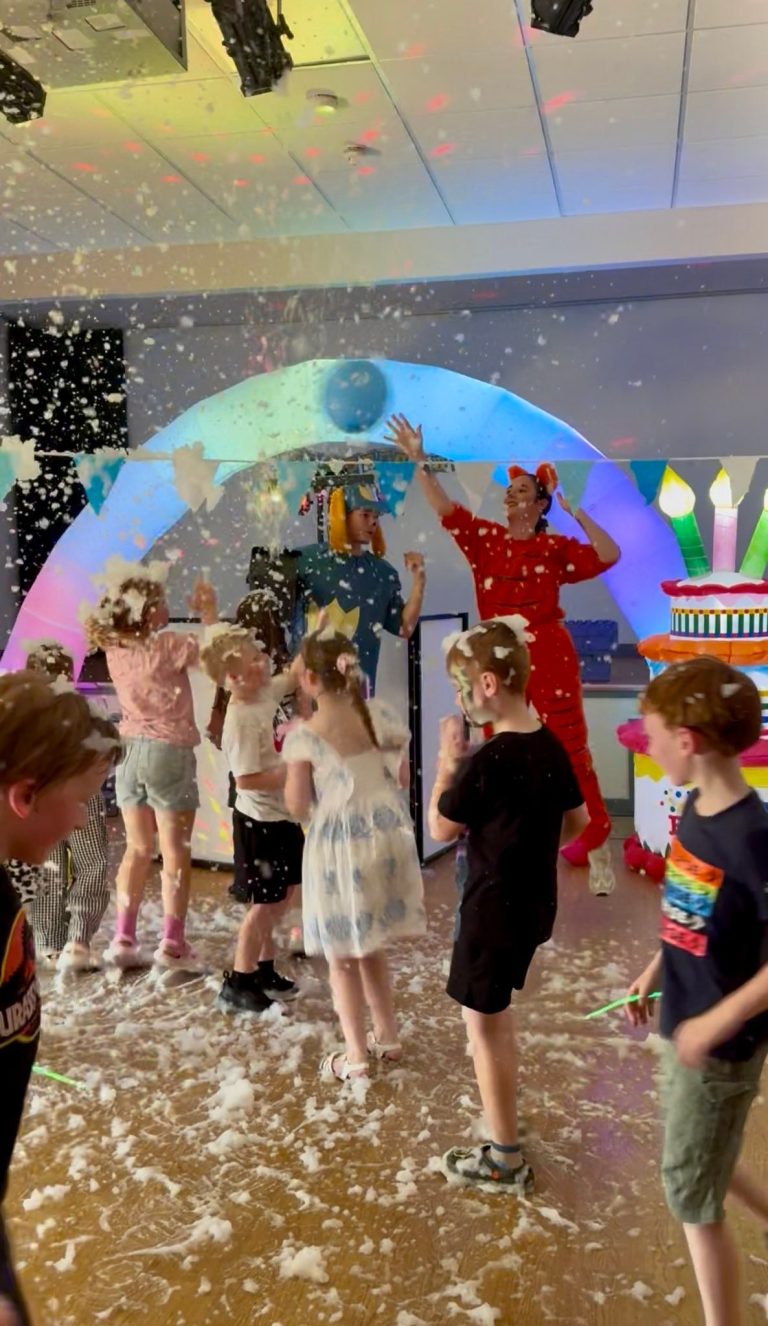Children dancing in foam and confetti at a Dog Man party