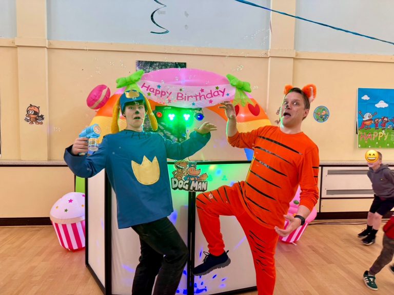 Dog Man and Petey the Cat entertainers posing in front of the DJ booth