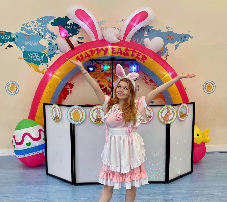 Bunny entertainer with arms wide under a Happy Easter bunny ears arch