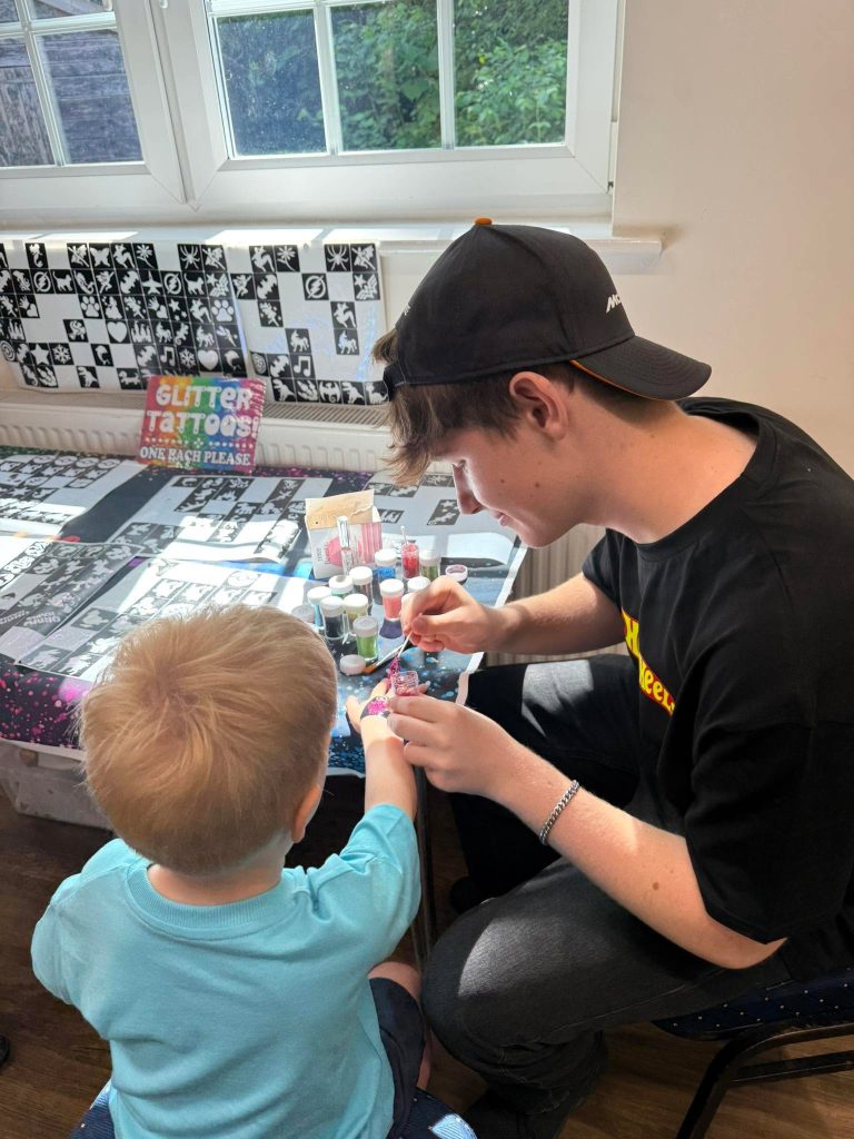 Glitter tattoo artist applying a tattoo for a child