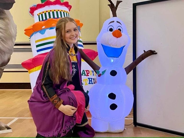 Anna entertainer kneeling beside an inflatable Olaf and birthday cake