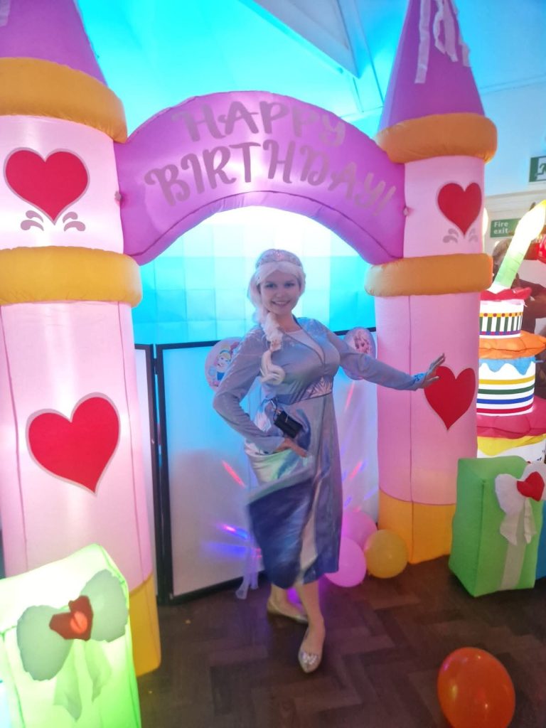 Elsa entertainer in a blue gown under a glowing princess castle arch