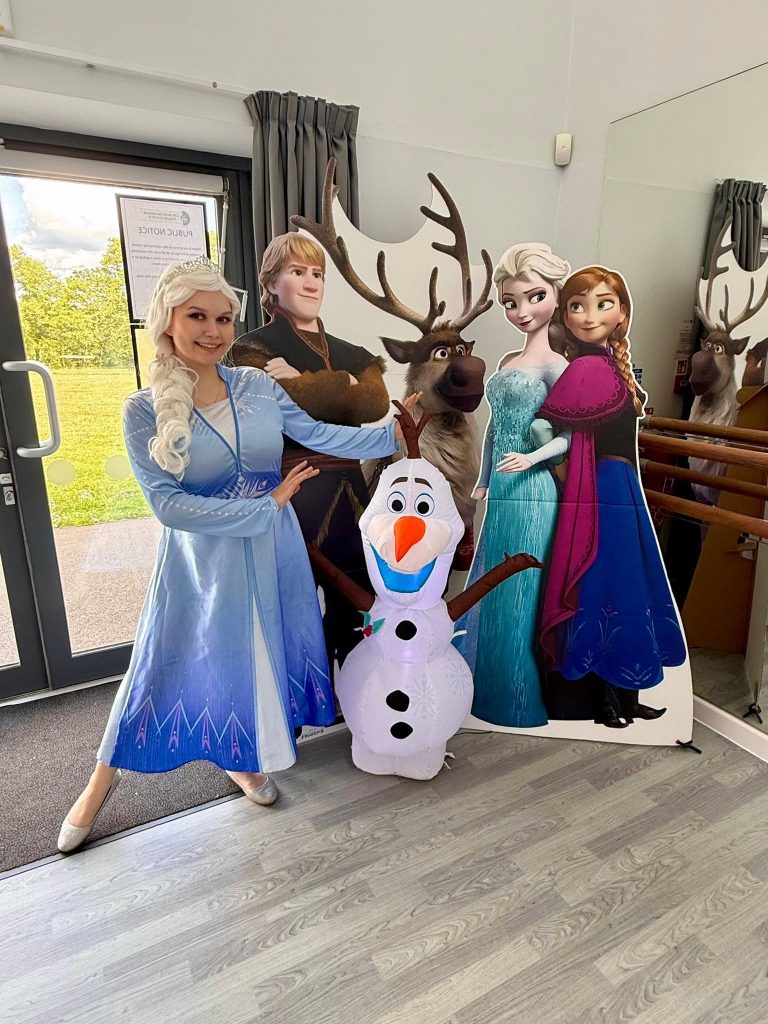 Elsa entertainer with Frozen cut-outs of Anna, Kristoff, Sven and an Olaf inflatable