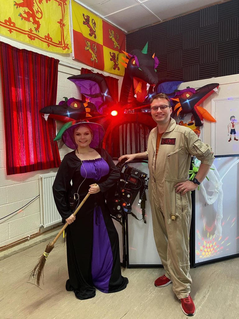 Witch and Ghostbuster entertainers in front of a dragon arch
