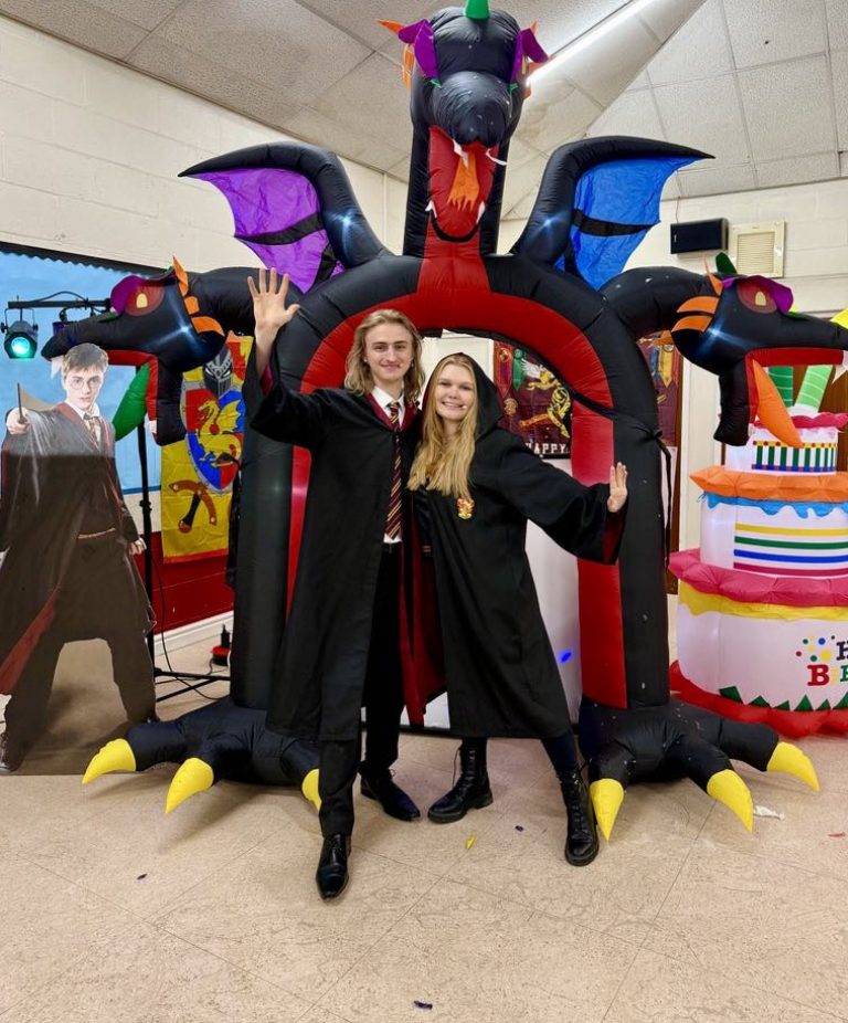 Two wizard entertainers in black robes under a dragon arch inflatable