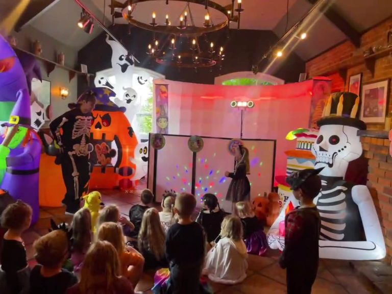 Hall decorated with Halloween inflatables and a wizard leading a party for children