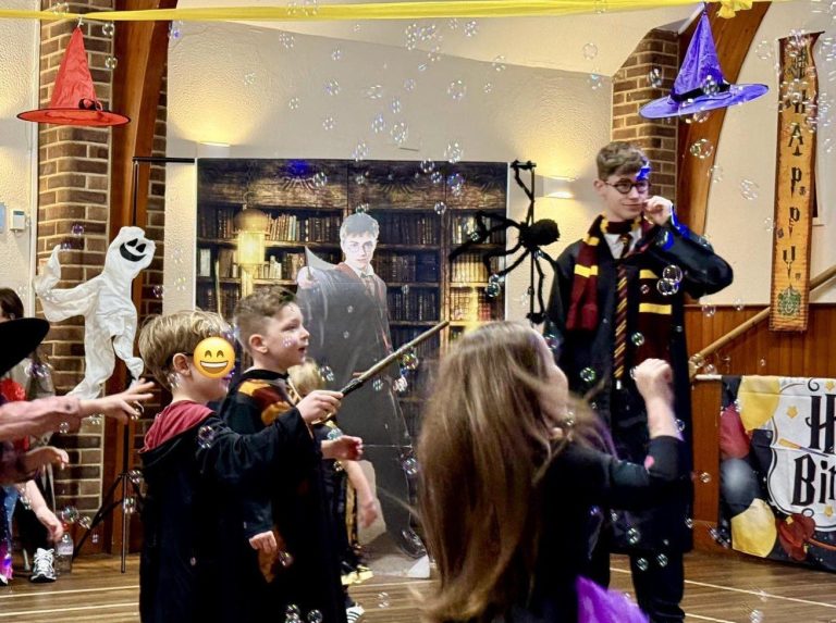 Wizard entertainer leading a wand game with children in a decorated hall