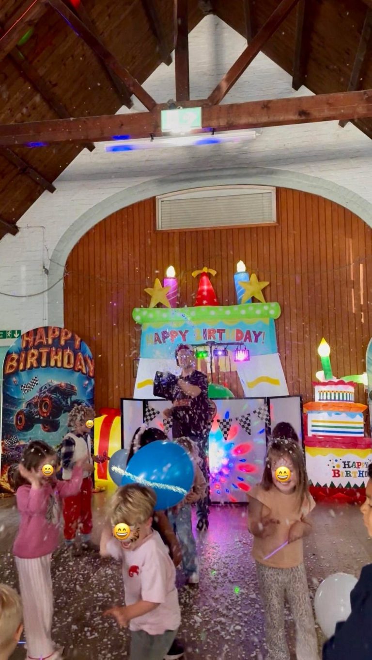 Children dancing and playing with balls in front of a Hot Wheels party setup