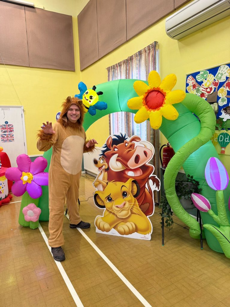 Lion entertainer under a flower arch with Lion King cut-outs