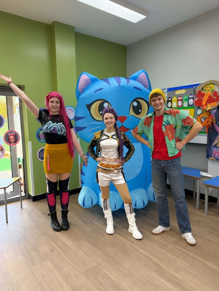Two K-Pop Demon Hunters entertainers posing with our giant Derpy Cat mascot at a children's birthday party