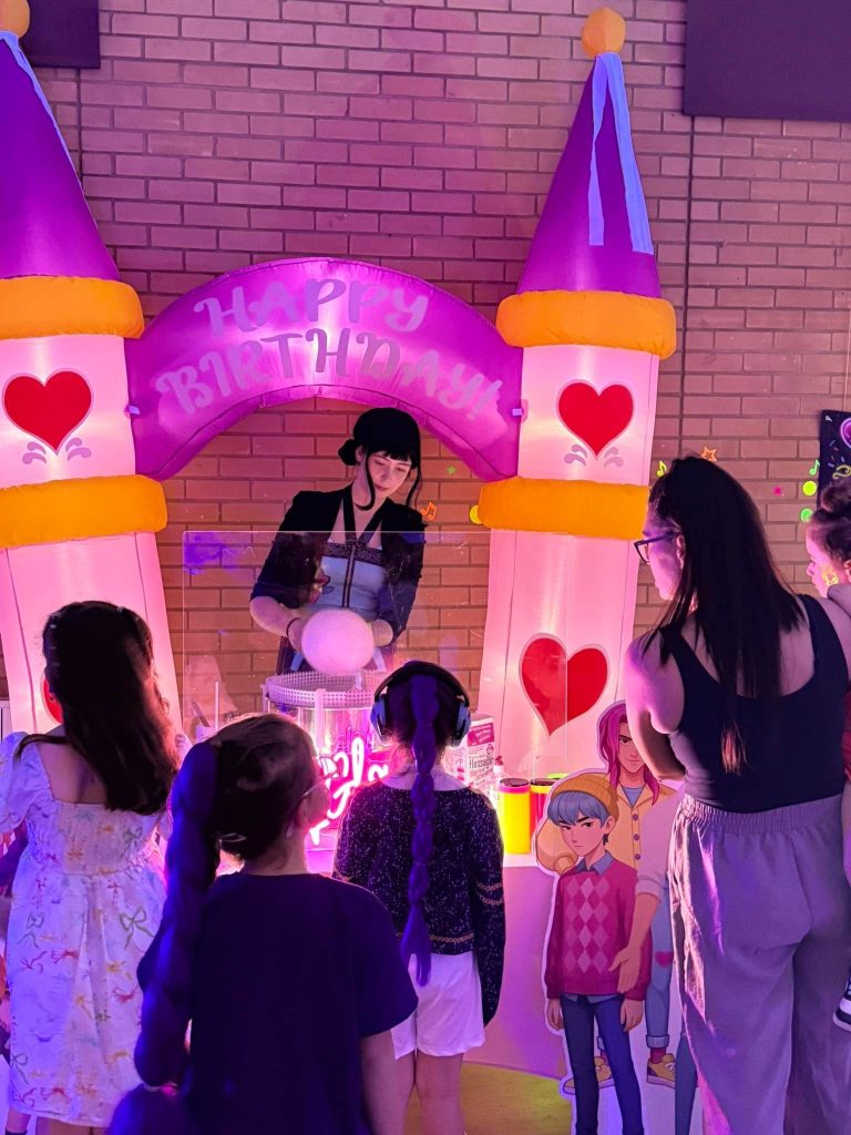 Entertainer making candy floss for children under a glowing castle arch