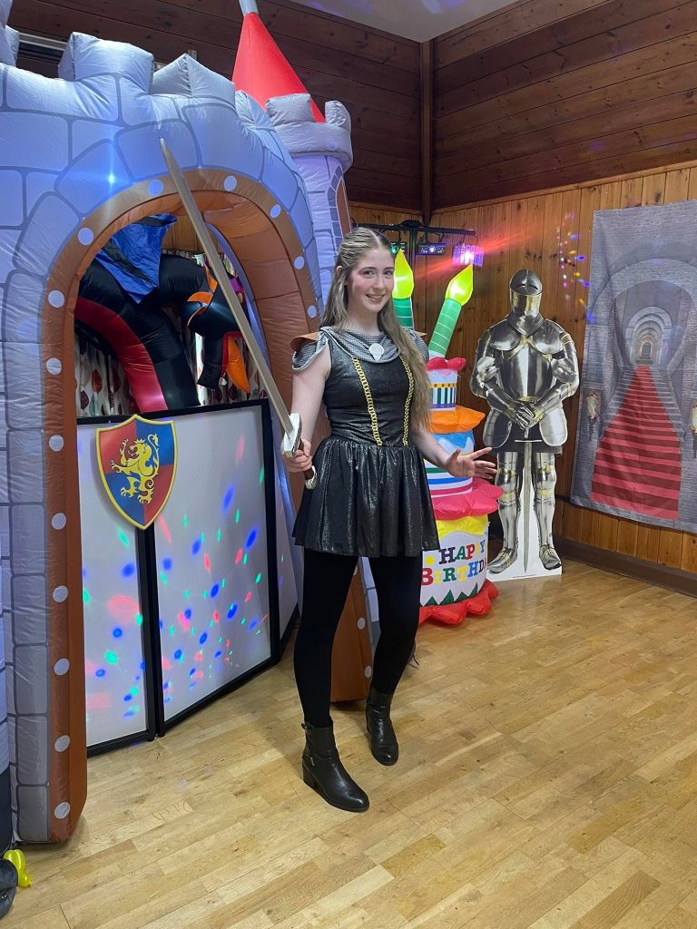 Knight entertainer in front of a castle inflatable with a suit of armour