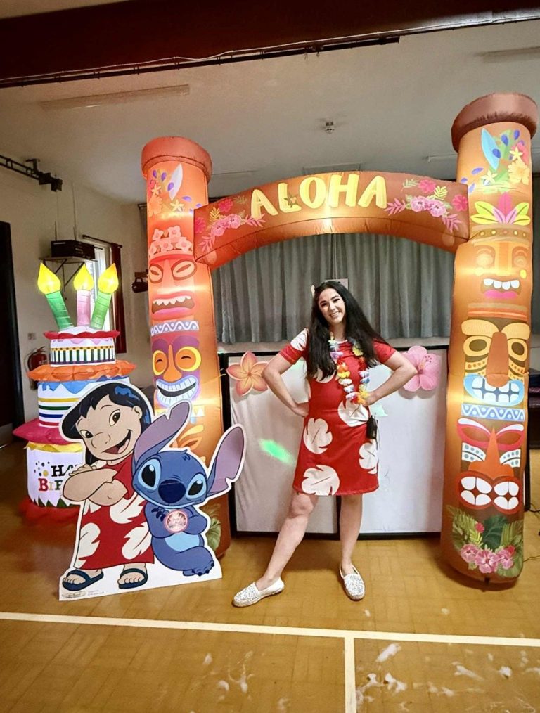 Lilo entertainer under an Aloha tiki arch with a Stitch cut-out