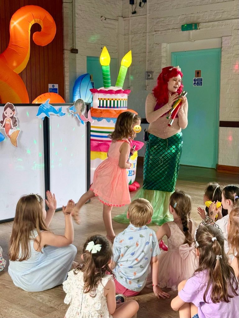 Ariel entertainer leading games with children sitting on the floor