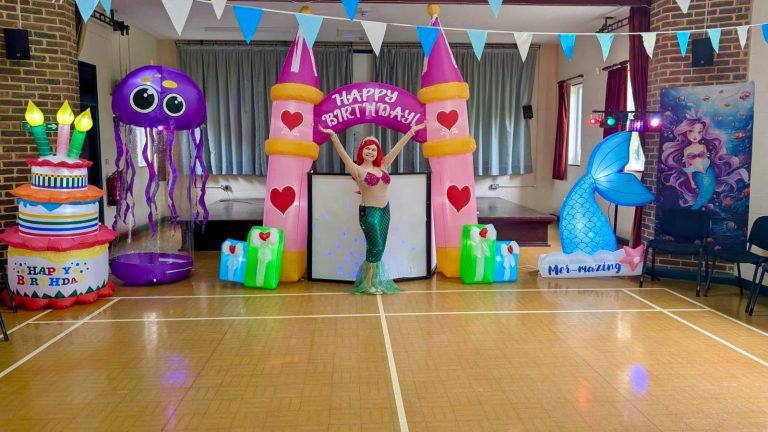 Ariel entertainer inside a princess castle arch with jellyfish and mermaid tail inflatables