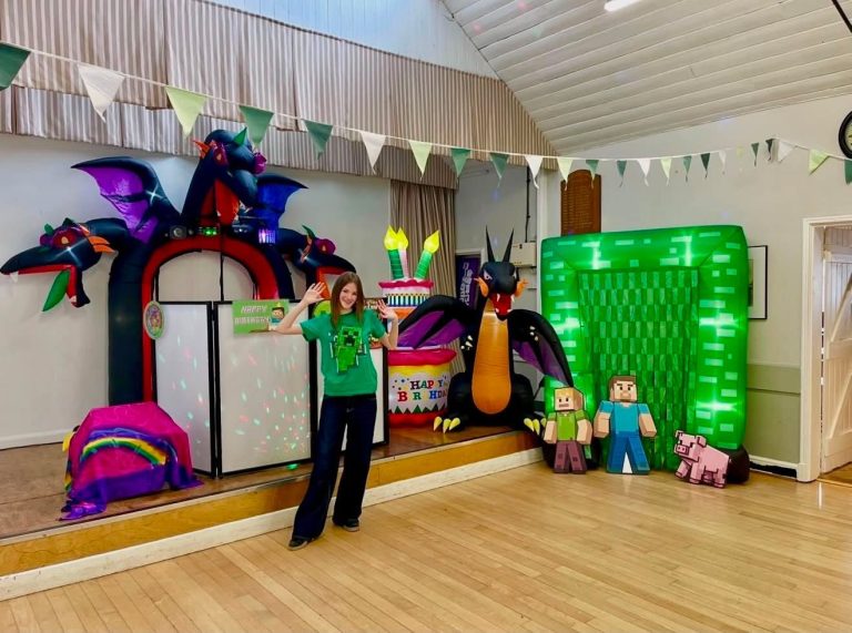 Minecraft party setup with dragon inflatables, character cut-outs and an entertainer on stage
