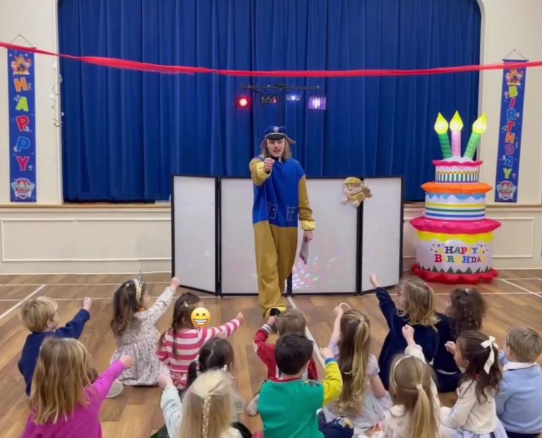 Entertainer performing for children in a hall decorated for a Paw Patrol party