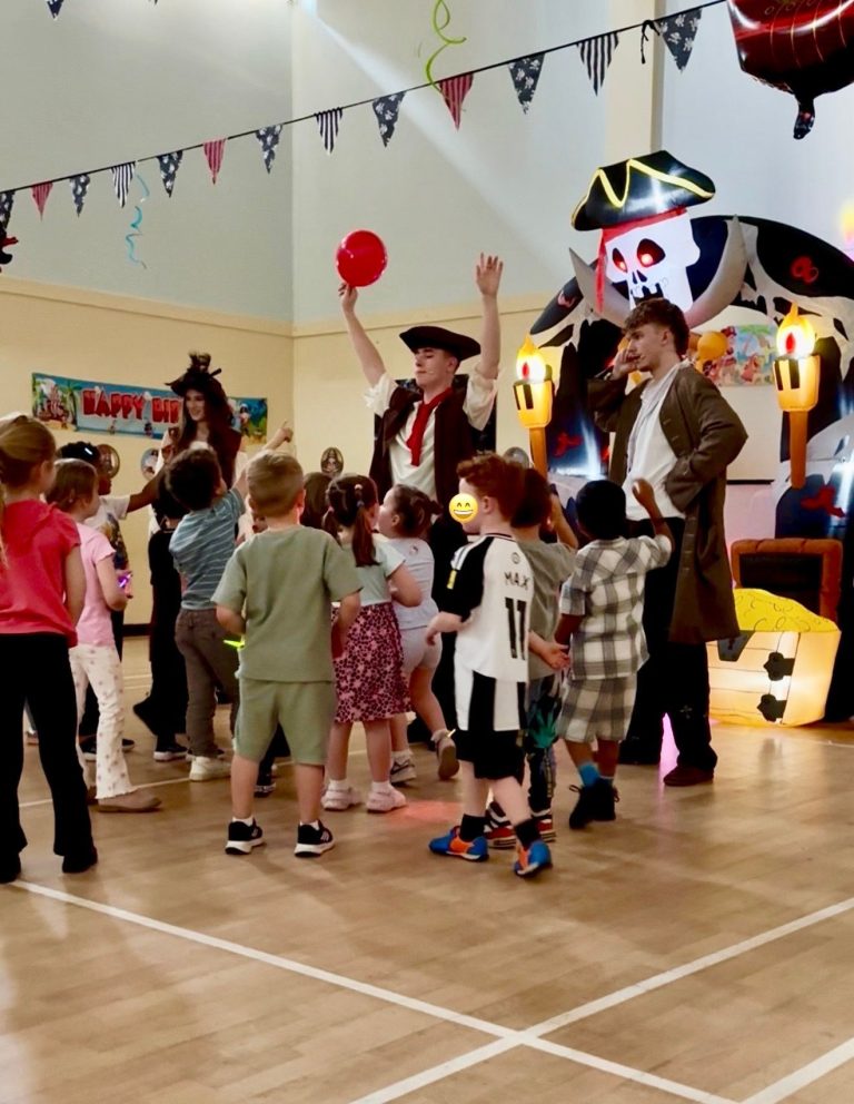 Pirate entertainers leading a dance game with children in a bright hall