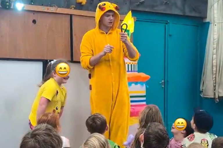 Entertainer in a Pikachu onesie performing magic to children