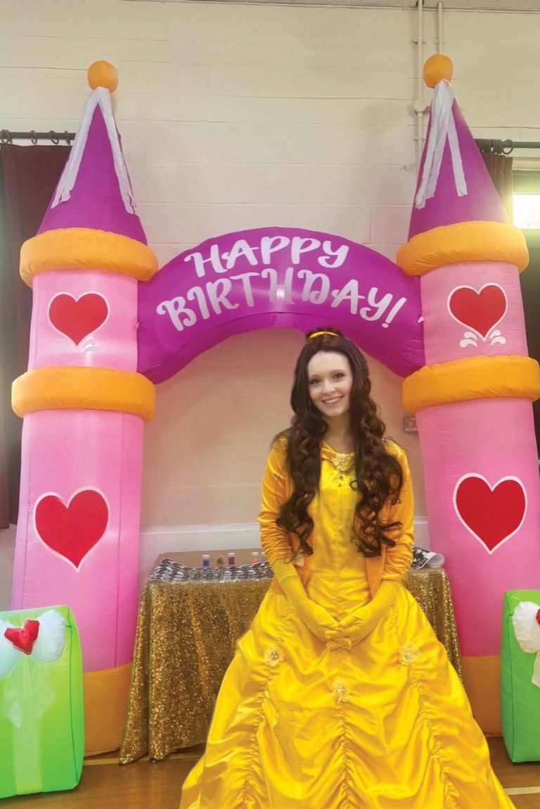 Belle entertainer in a yellow ball gown under a pink princess castle arch