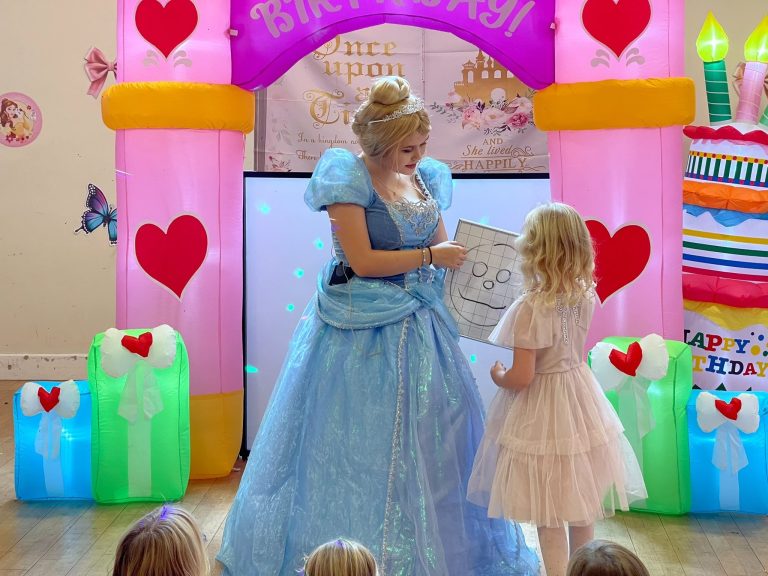 Cinderella performing a magic trick with a birthday girl in front of a castle arch