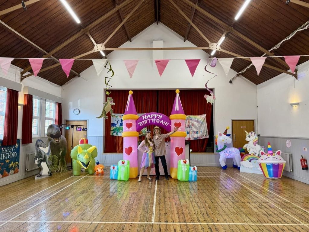 Princess party setup - Treasure Box Parties Princess castle arch, unicorn and cupcake inflatables set up in a village hall