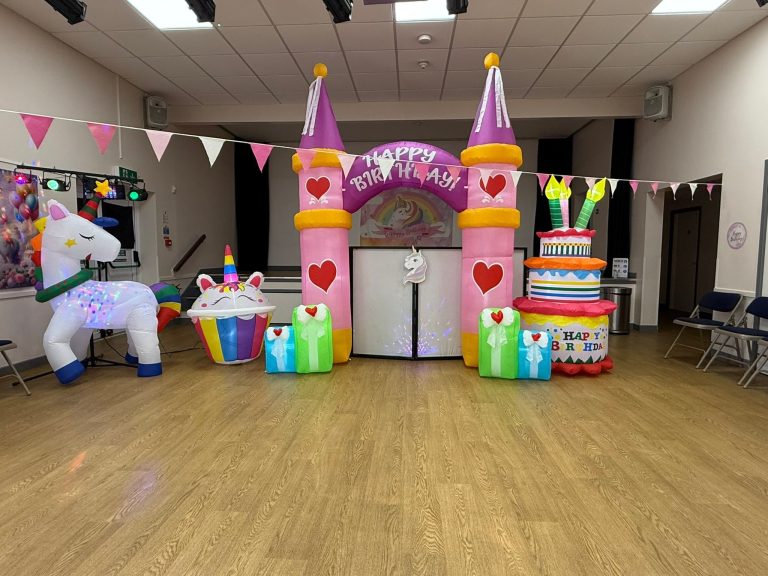 Wide view of a princess castle arch, unicorn and cupcake inflatables