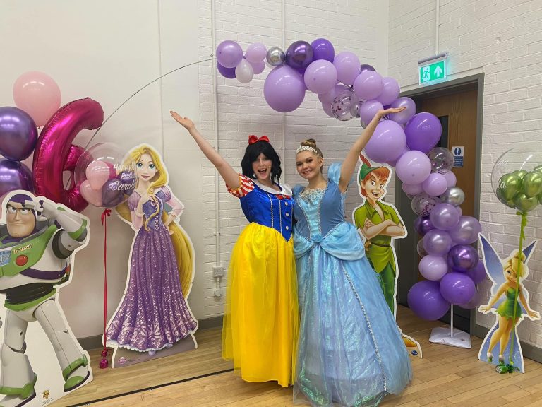 Snow White and Cinderella entertainers in front of a purple balloon arch with Disney cut-outs