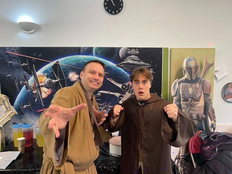 Two Jedi entertainers posing in front of a Star Wars mural