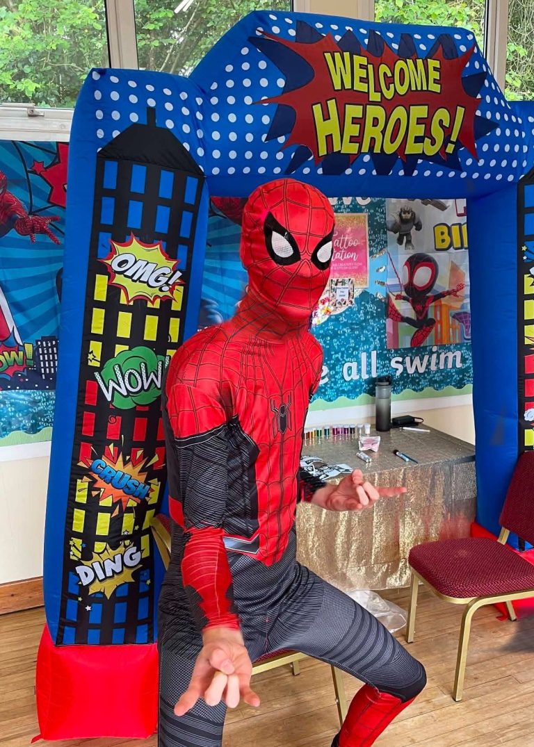 Spider-Man entertainer posing under a Welcome Heroes comic-book arch