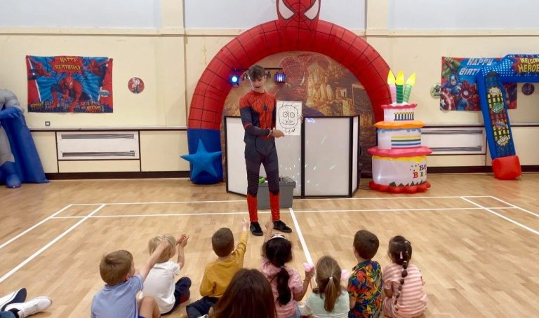 Wide view of a Spider-Man magic show with children watching in a sports hall