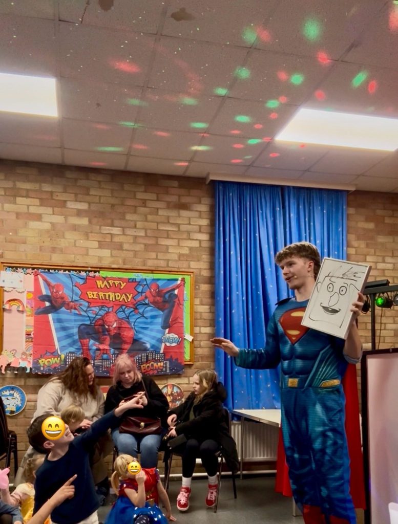 Superman's magic show - Treasure Box Parties Superman entertainer holding a magic drawing board in front of seated children