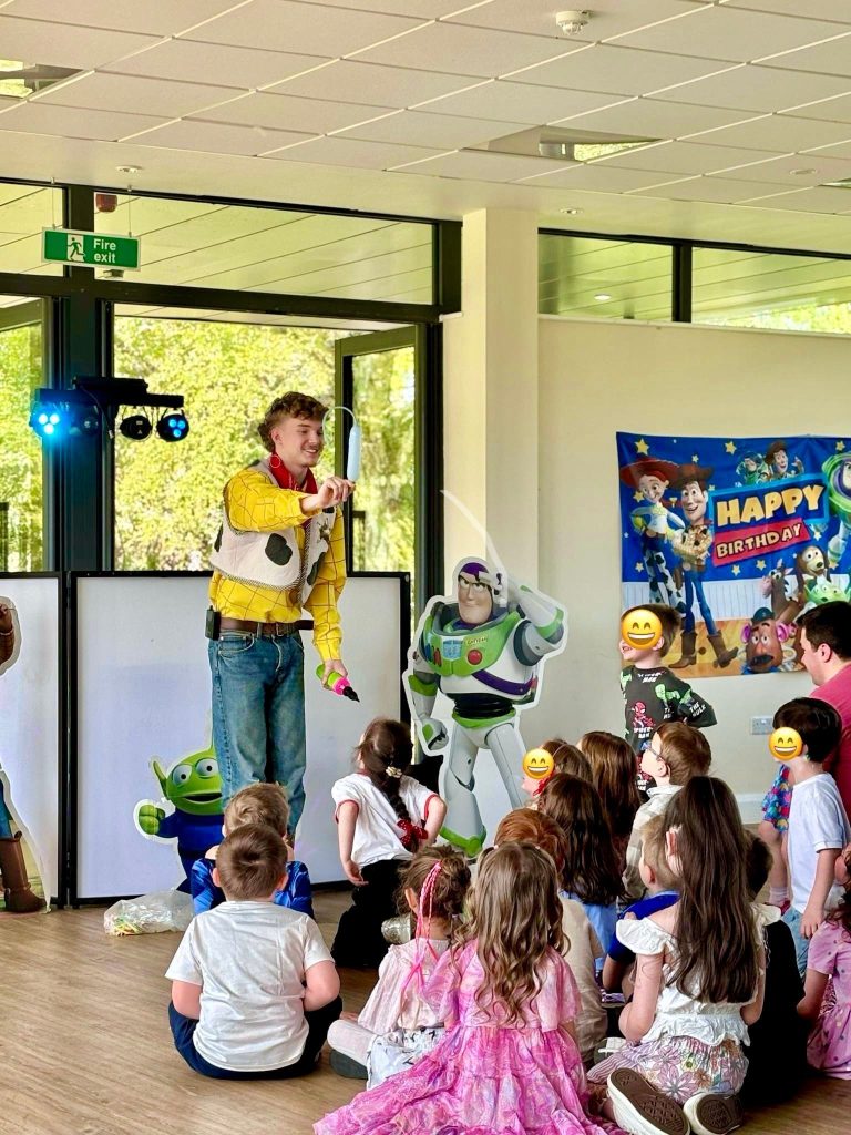 Woody entertainer performing for seated children with Buzz cut-outs and Toy Story banner