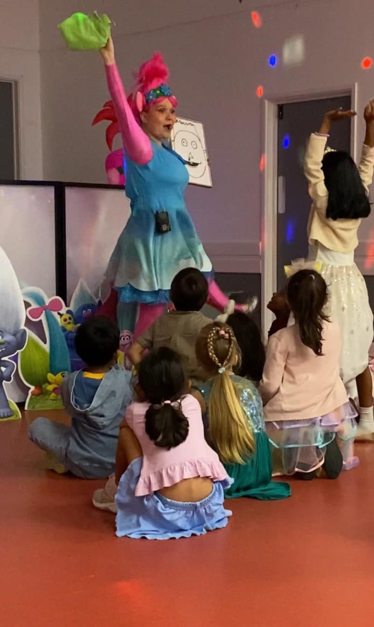 Poppy entertainer dancing with children sitting on the floor