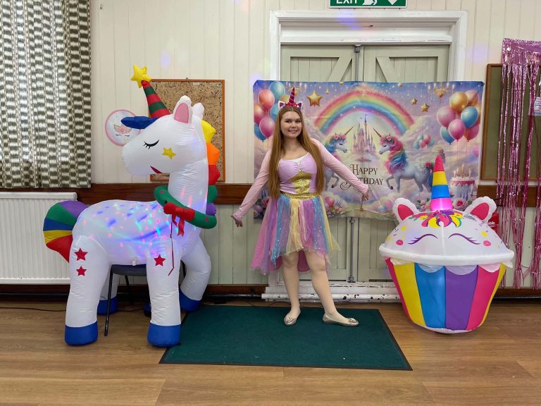 Unicorn fairy entertainer between a unicorn inflatable and a cupcake inflatable