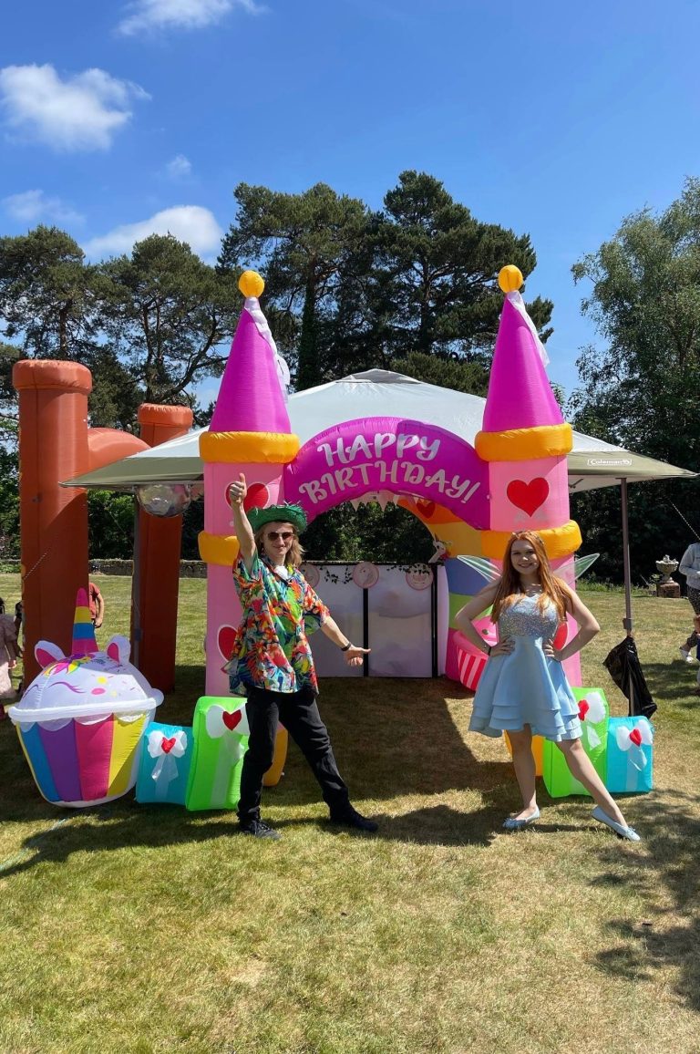 Fairy and DJ entertainers at a garden party with a castle arch and unicorn inflatables