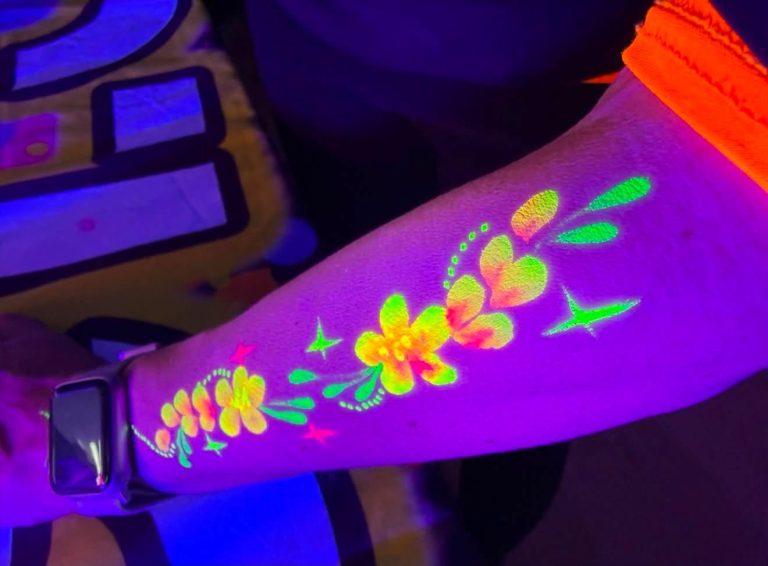 Close-up of glowing UV body paint flowers and stars on an arm